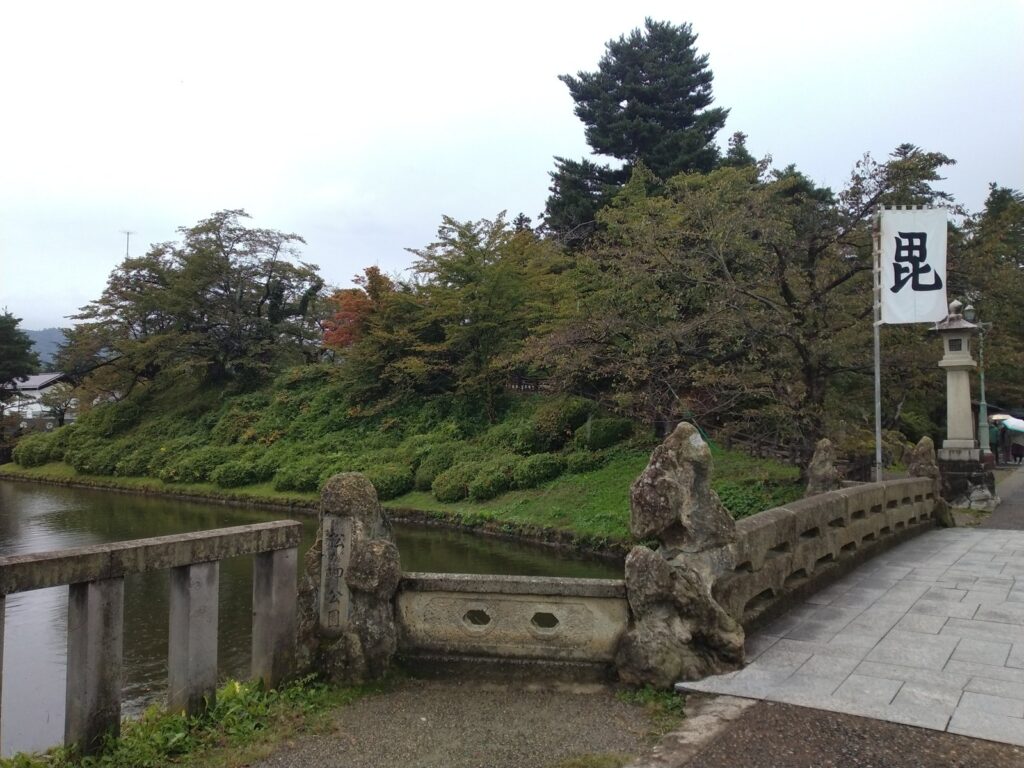 米沢城跡の堀と、上杉神社へ向かう舞鶴橋。「毘」の旗が立つ